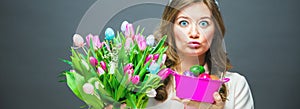 Cheerful young woman with bunny ears and Easter egg basket and tulips Flowers Looking at camera