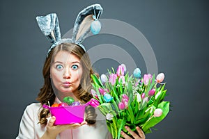 Cheerful young woman with bunny ears and Easter egg basket and tulips Flowers Looking at camera