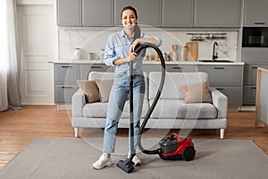 Happy woman standing with vacuum cleaner at home