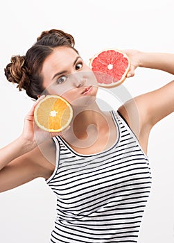 Cheerful young woman with citrus fruit, put to the face. Cheerfulness and good mood photo