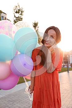 Cheerful young woman with color balloons on sunny day