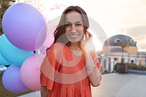 Cheerful young woman with color balloons on sunny day