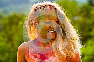 Cheerful young woman with colorful paint on face and bodies having fun at holi festival. Laughing young woman with color