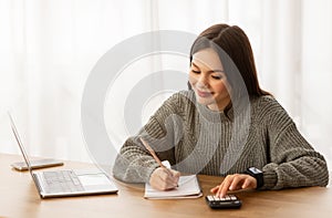 Cheerful young woman counting her monthly spendings