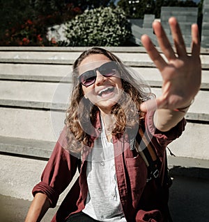 Cheerful young woman with dark curly hair enjoying holiday in city, Beautiful girl pulls hands into the camera