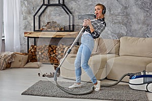 Cheerful young woman enjoying solo singing with vacuum cleaner while cleaning house