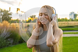 Young woman enjoys listening to music and singing while sitting in park
