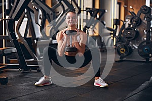 Cheerful young woman exercising buttocks in gym