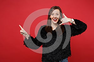 Cheerful young woman in fur sweater doing phone gesture like says call me back, pointing index finger aside isolated on