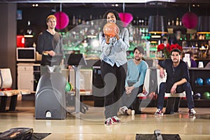 Cheerful young woman goes bowling with her friends