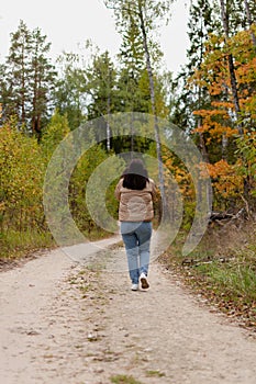 cheerful young woman in a gray jacket on the background of an autumn landscape