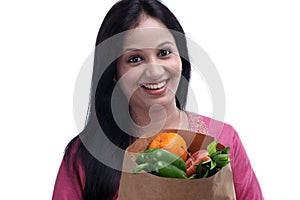 Cheerful young woman with a grocery bag full of fruits and vegetables