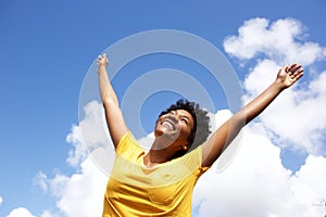 Cheerful young woman with hands raised towards sky