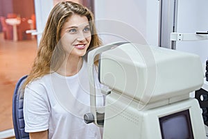 Cheerful young woman having eye examining in clinic