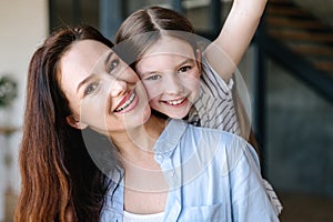 Cheerful young woman having fun with daughter at home