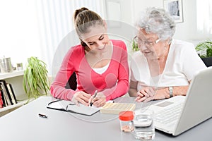 Cheerful young woman helping an elderly woman with pills medical prescription