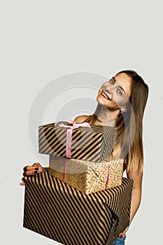 Cheerful young woman holding heap of presents, looking at camera, isolated on white background