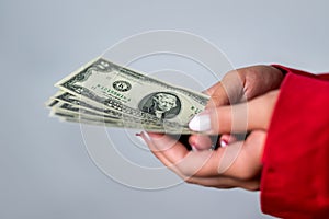 cheerful young woman holding money dollar bills in office isolated on plain background.