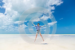 Cheerful young woman in joy jumping with arms out over desert sea lagoon