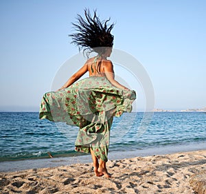 Cheerful young woman jumping joyfully on a beach in Sardinia, Italy, on a beautiful sunny day