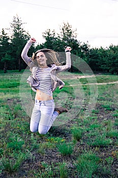 Cheerful young woman jumping on the meadow