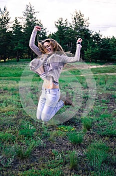 Cheerful young woman jumping on the meadow