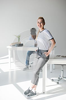 cheerful young woman leaning at table and smiling at camera