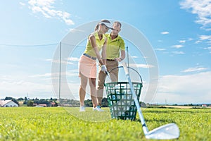 Cheerful young woman learning the correct grip and move for using the golf club