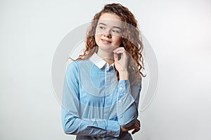 Cheerful young woman with long curly red hair thinking about something.