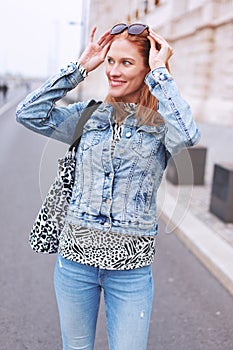 Cheerful young woman looking aroun on street in city
