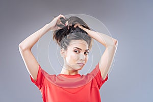 Cheerful young woman looking glad while changing her hairstyle