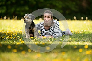 A cheerful, young woman lying on the grass with her pet.