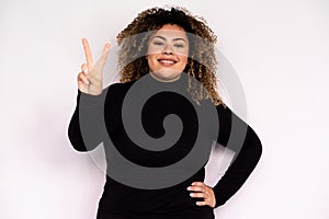 Cheerful young woman making peace sign with her hand