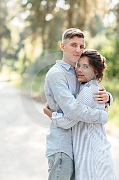 Cheerful young woman and man are hugging outdoors in summer park. couple in love having date and romantic vacation on sunny day.