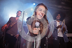 Cheerful young woman with musicians performing at nightclub