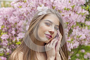 Cheerful young woman with natural makeup and healthy long brown hair in blossom park outdoors. Natural female beauty portrait