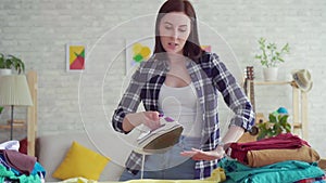 Cheerful young woman in plaid shirt ironed linen iron at home ,dancing close up