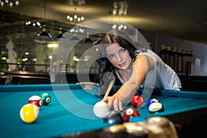 Cheerful young woman playing American billiards