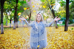 Cheerful young woman playing with autumn leaves photo