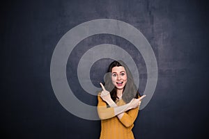 Cheerful young woman pointing fingers away