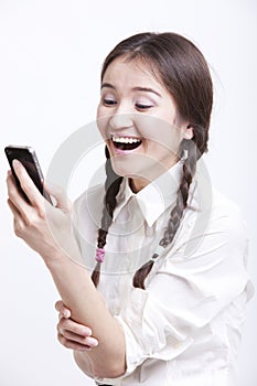 Cheerful young woman reading text message on her cell phone against white background