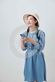 Cheerful young woman reading text message on her cell phone against white background