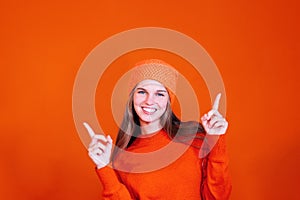 Cheerful young woman on red background advertising pointing fingers up