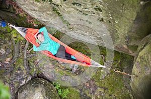 Cheerful young woman relaxing in hammock near cliff