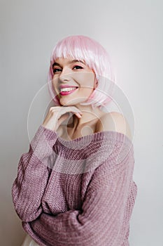 Cheerful young woman with shiny light-pink hair smiling on light background. Indoor portrait of gorgeous female model in