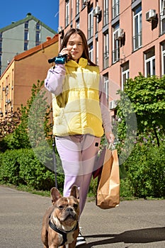 Cheerful young woman shopping while dog walking at city in sunny day