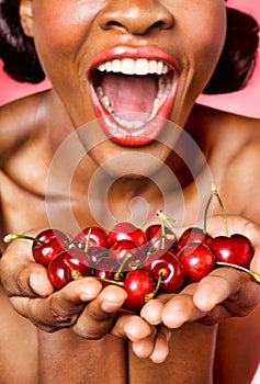 Cheerful young woman showing cherry in her hands