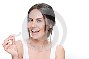 Cheerful young woman showing clear aligner