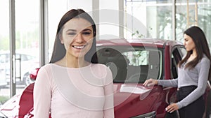 Cheerful young woman showing thumbs up holding car keys