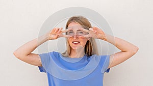 Cheerful young woman showing V-signs near her eyes